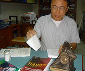 Macario Tiu in his Ateneo office. Before him is a copy of his book and the National Book Award trophy (davaotoday.com photo by Tyrone Velez)