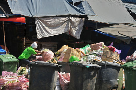 NO SEGREGATION. Davao City’s implementation of the solid waste management law remains a test, as this man in Magallanes public market is seen dumping just about any kind of trash inside these bins that have been color-coded to segregate non-biodegradable and biodegradable wastes. (davaotoday.com photo by Mick M. Basa)