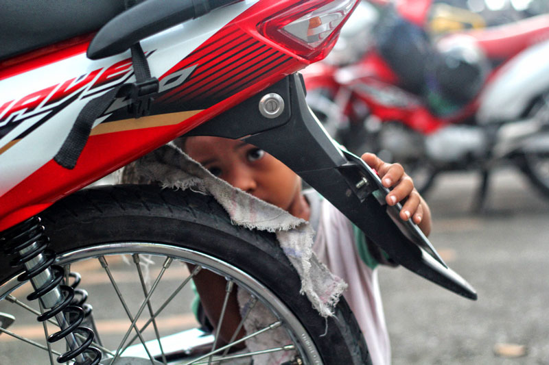 CHILD AT WORK.  Ryan says he earns PHP 10 for every motorcycle he cleans outside the Davao City Hall.  (davaotoday.com photo by Ace R. Morandante)
