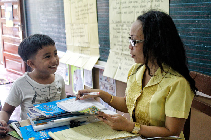 FIRST DAY HIGH.  A Grade 3 pupil in Davao City’s Kapitan Tomas Monteverde Elementary School submits his notebook to his teacher for checking on Monday, the first day of school year 2013-14.  (davaotoday.com photo by Medel V. Hernani)