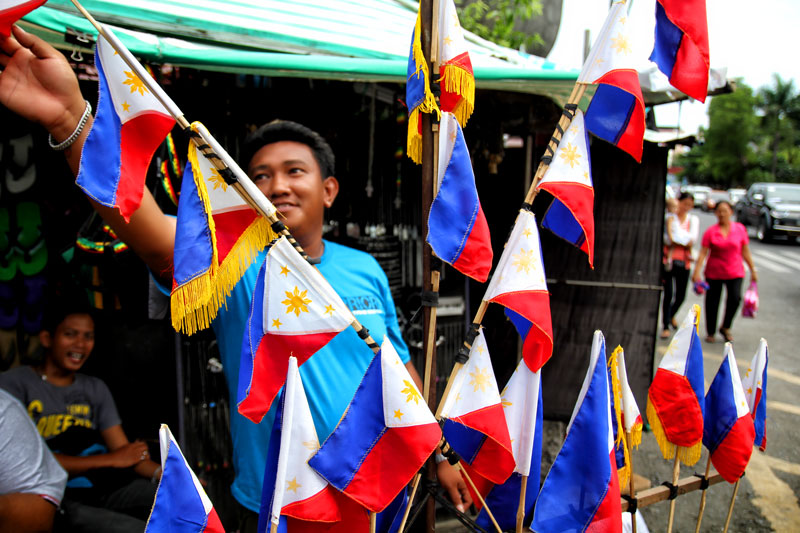 ON SALE.  A vendor sells miniature Philippine flags along Davao City’s San Pedro Street.  On Wednesday, the country celebrates the 115th Independence Day.  However, militant umbrella organization Bayan said “Under the Aquino regime, we have a lethal combination of sham independence and sham development.  Despite the repeated claims of economic growth, our people remain mired in crisis…created by our lack of economic sovereignty.”  (davaotoday.com photo by Ace R. Morandante)