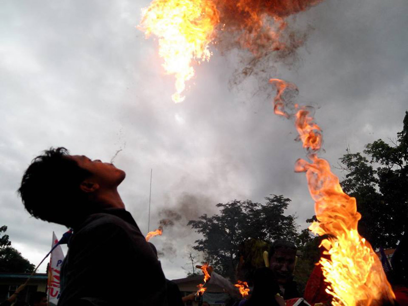 FIRE WITH FIRE Protester spits fire as Bayan activists burn Aquino’s effigy (background) in Davao’s SONA protest in Rizal Park (davaotoday.com photo by John Rizle L. Saligumba) 
