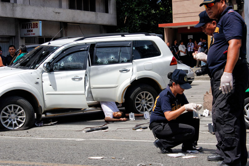 CLEANING UP. Police officers collect empty shells in the scene of the rescue operation of a kidnapped Filipino-Chinese businesswoman in downtown Davao City that ended with the deaths of three kidnappers.  (davaotoday.com photo by Medel V. Hernani)