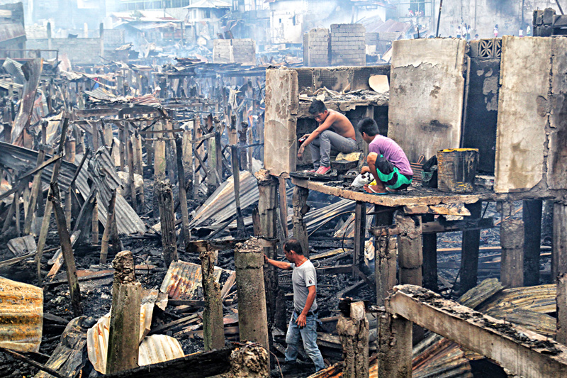 AFTER THE FIRE A family scours through burned debris in their home after Thursday's fire that razed 200 houses in a crowded and narrow settlement from Fatima Village, Km 11, Zone 5 Sasa through Purok 1, Muslim Village. (davaotoday.com photo by Ace R. Morandante)
