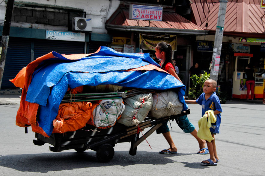 PUSHCART FOR A LIVING A teenage girl and young brother bear the midday sun as they push their cart full of ukay-ukay goods from Bankerohan public market to Magallanes Street. (davaotoday.com photo by Medel V. Hernani)