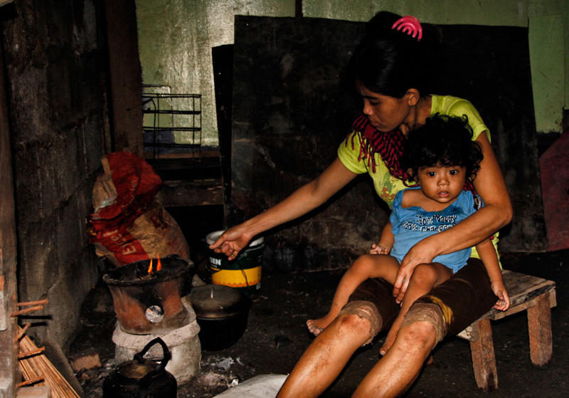 MULTITASKING. A house at the Boulevard street bears this mother who does everything-- from caring the toddler to cooking with a charcoal stove.(davaotoday.com photo by Medel V. Hernani)