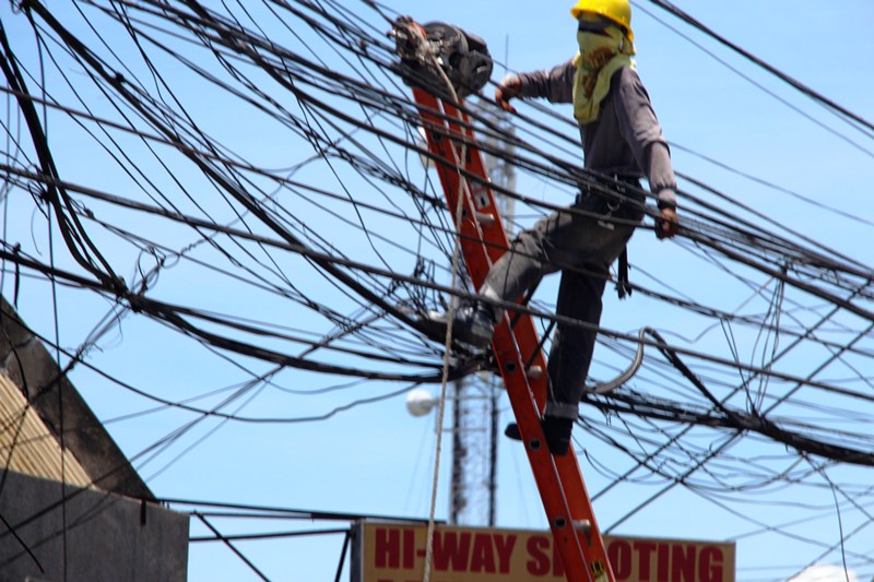 An electric line man braves the midday heat as he fixed a line in an intersection along JP Laurel Avenue Davao City (davaotoday.com photo by Medel V. Hernani)