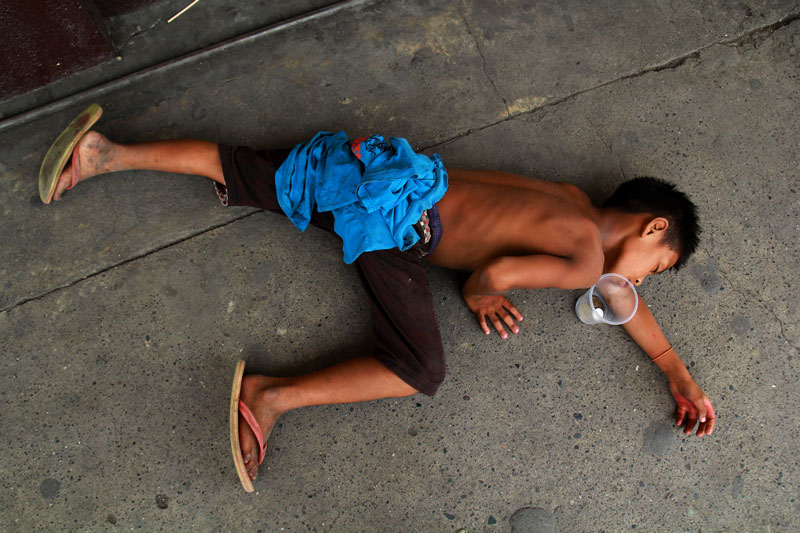 A street kid falls asleep while waiting for pennies to drop on his cup. Poverty has increased in Davao City in the past year. (davaotoday.com photo by Ace R. Morandante)