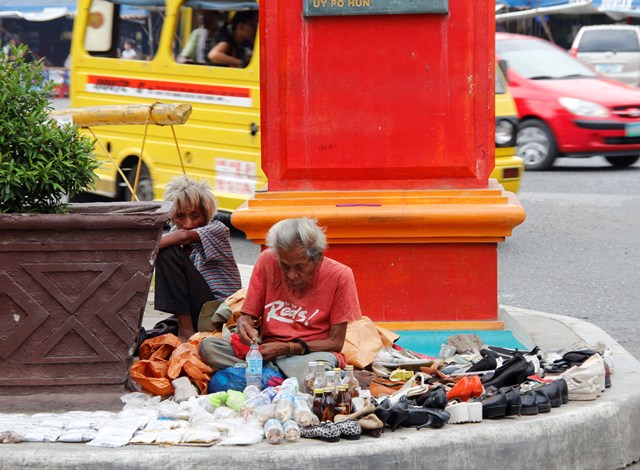 OLD VENDOR An elder vendor sells old shoes under Davao's Chinatown archway in Magsaysay Avenue. (davaotoday.com photo by Medel V. Hernani)