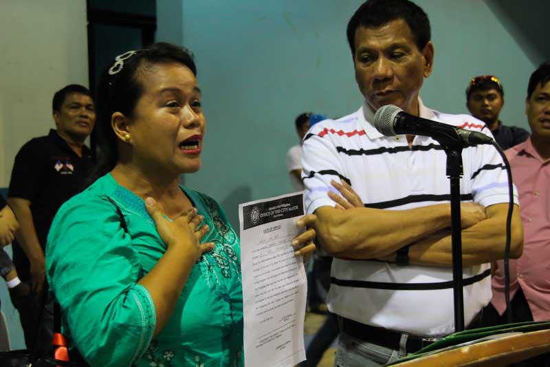 TACLOBAN OFFICIAL THANKS DUTERTE An elected barangay official from Tacloban, Leyte, Jessica Seno Panis (left) cries as she thanks Davao City Mayor Rodrigo Duterte (right) for including her during Friday’s oath taking ceremony of new barangay officials at Almendras Gym.  Panis is temporarily residing with relatives in Davao after Typhoon Yolanda ravaged her city and other parts of Eastern Visayas, but said she will return soon to serve her constituents in Barangay 73 PHHC. (davaotoday.com photo by Ace R. Morandante)