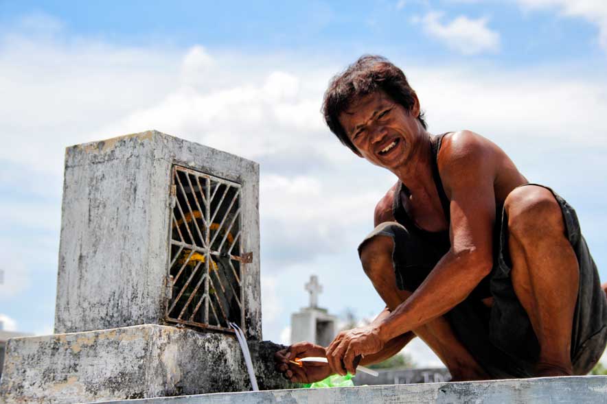 LIGHTING A CANDLE In Tibungco Cemetery, a man stoops atop a tomb to light a candle for his departed family member during the weekend's observance of All Souls Day. (davaotoday.com photo by Medel V. Hernani)