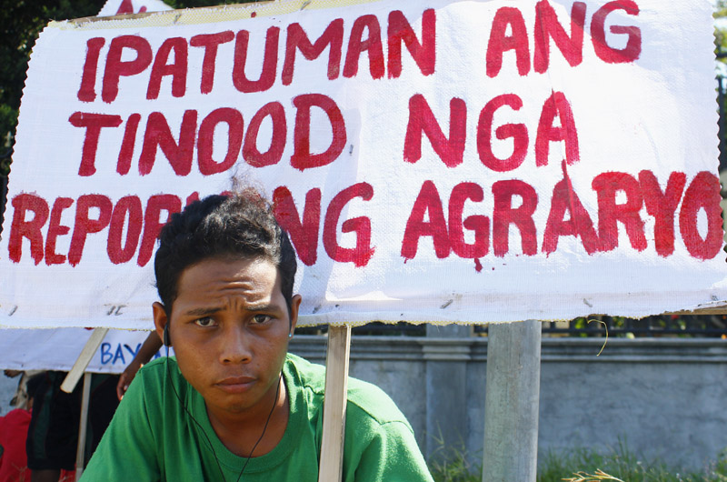 A farmer carries a sign demanding for agrarian reform to benefit farmers during a human rights rally in Digos City.