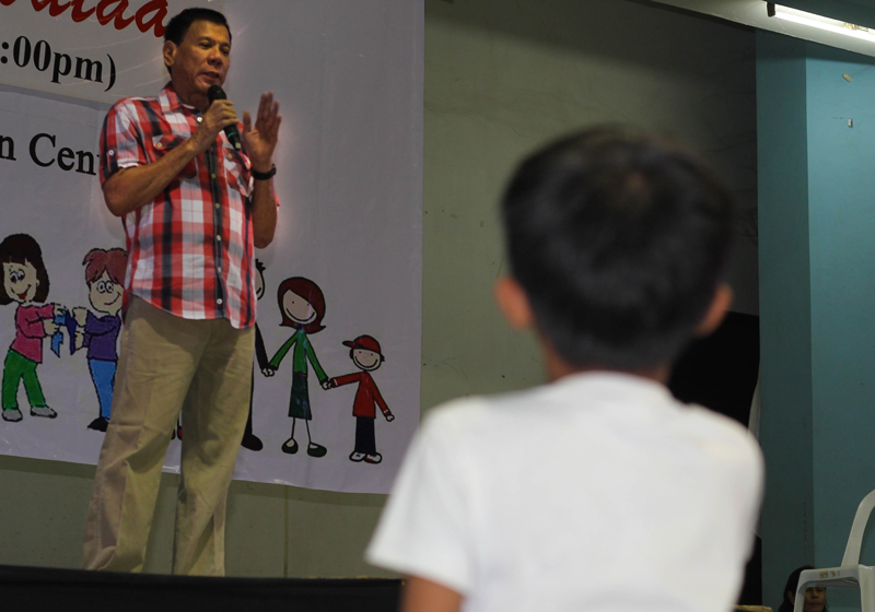 ALL EYES ON MAYOR A boy listens to Mayor Rodrigo Duterte as he gives his message during the city’s Christmas treat to poor children last Monday at Almendras Gym. (davaotoday.com photo by Ace R. Morandante)
