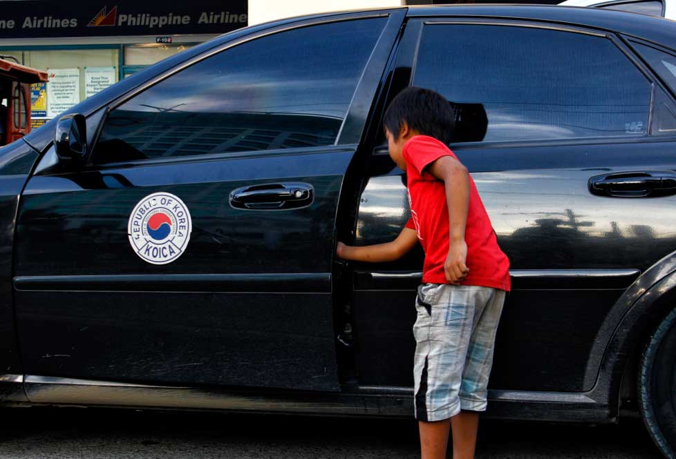 KNOCKING ON YOUR CAR  This child is unmindful of the risk of going around a busy intersection to ask for money from motorists. (davaotoday.com photo by Medel V. Hernani)