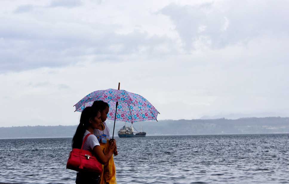 WATCHING THE SEA Mother carries his toddler as they brace the wind and view the sea along Magsaysay Park shore in a cloudy afternoon. (davaotoday.com photo by Medel V. Hernani)