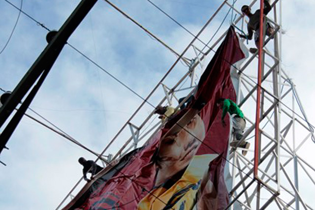 HIGH RISK. Risking their lives atop the heights, workers synchronize their moves as they install a tarpaulin for an advertisement. (Medel Hernani/ davaotoday.com)