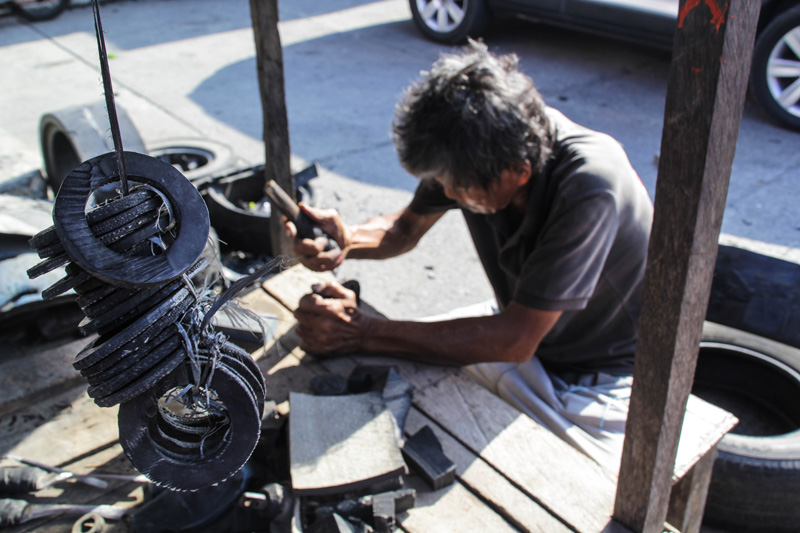 RUBBER WORKS. Manong Lito, 64, tirelessly crafts rubber boss out of worn-out tires in his street shop along Acacia St., Davao City. (Ace R. Morandante/davaotoday.com)