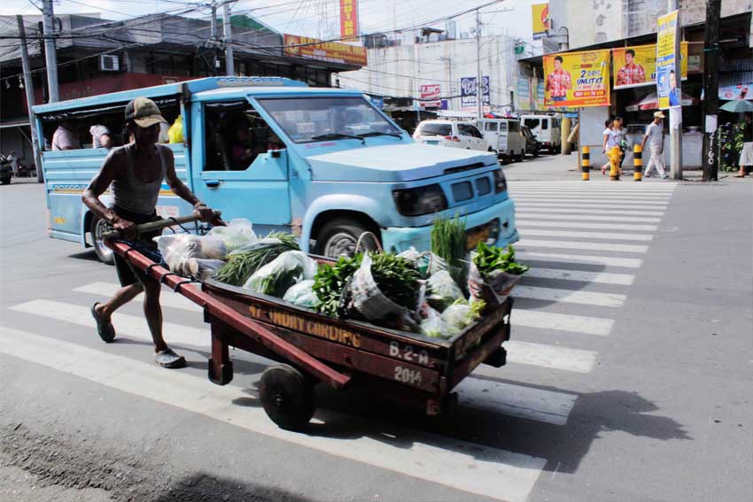  A market porter bears the morning heat to make his daily delivery of fresh vegetables from Bankerohan to Mabini market, which earns him some 100 pesos for his labor. 