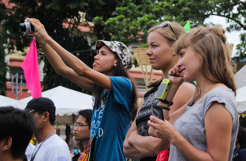 Three foreigners watch as 11 tribes take turn in culture presentations at the Rizal Park. The activity is part of the week-long 29th Kadayawan fruit harvest festival.