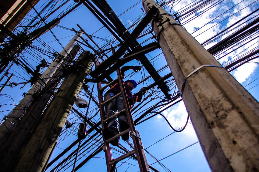 Never minding the perils of his job, a cable worker fixes damaged wires along Ponciano street. 