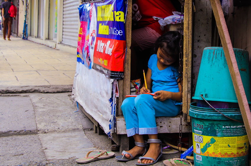 A child catches up with school studies while tending to their little sidewalk store along Palma Gil Street in downtown Davao City.