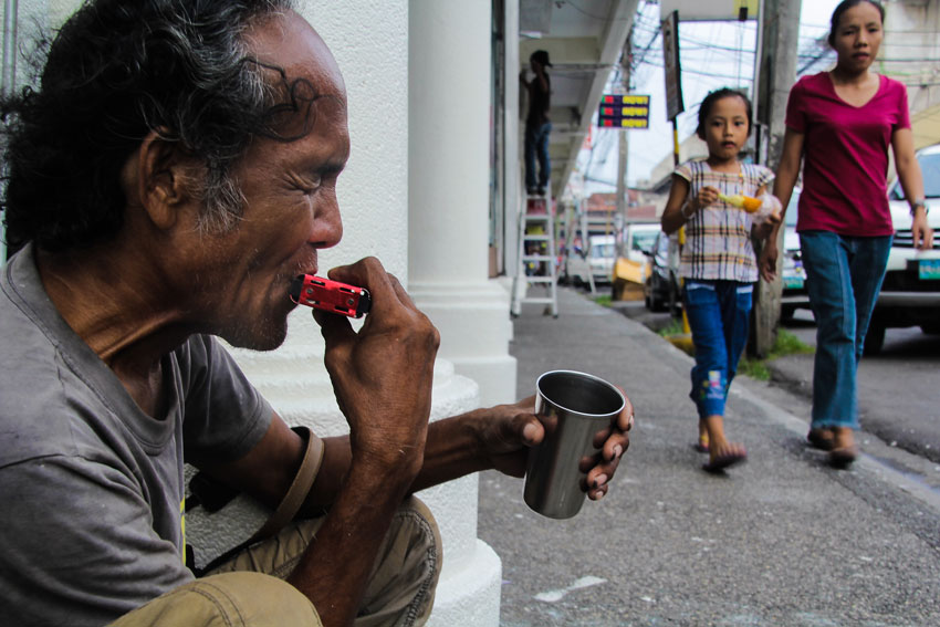 A beggar on the street of Bolton is playing his harmonica in exchange for some coins from instant listeners. (Ace R Morandante/davaotoday.com)