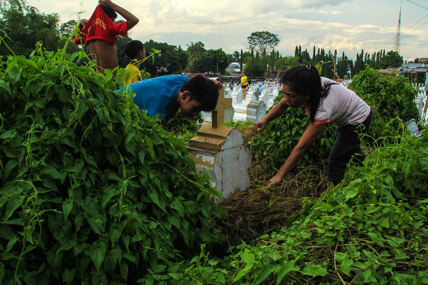 This family cleans up grass and dirt at the grave of their loved ones at Wireless Cemetery. (Ace R. Morandante/davaotoday.com)