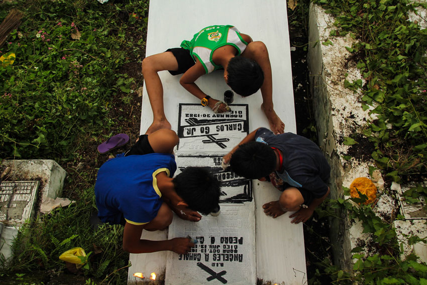 These boys maximize the day to gain money by painting the tombstones at the Wireless Cemetery. (Ace R. Morandante/davaotoday.com)