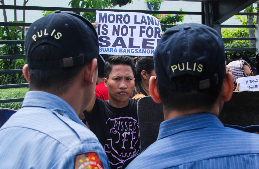 NOT FOR SALE. A member of the Suara Bangsamoro group raises a call while police maintain their guard outside the SM Lanang Premier. The government and the Moro Islamic Liberation Front conducted a Philippine Development Forum on November 5-6, intended to generate funding support to a development plan for Moro-populated areas in Mindanao. (Ace R. Morandante/davaotoday.com)