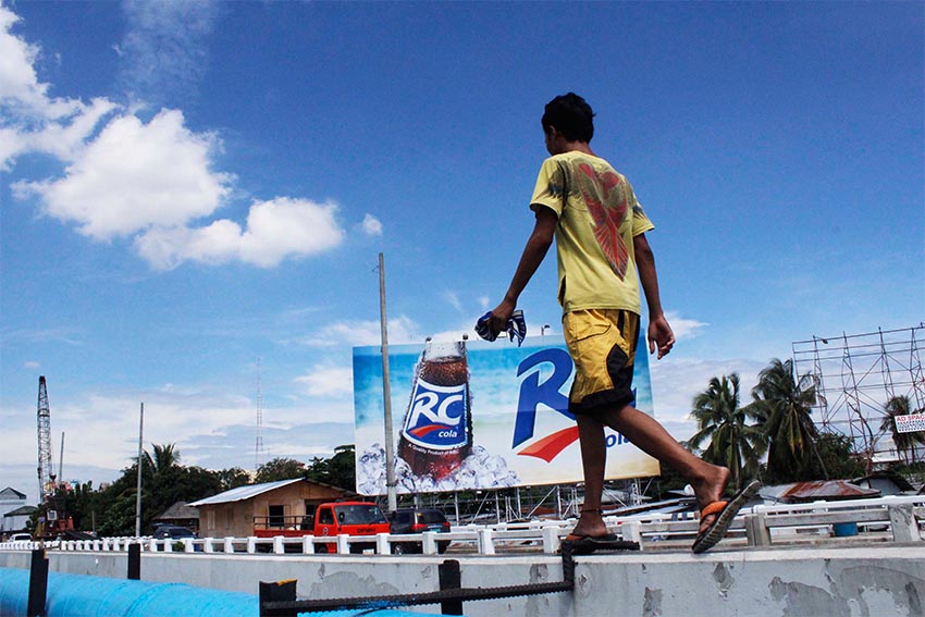 A man traversing Governor Generoso Bridge walks on top of the concrete railing of the Bridge 1 in  going to Bankerohan while workers fast-tracked the major repair of the second bridge with hope to open it to regular traffic this coming Monday, November 17. (Medel V. Hernani/davaotoday.com)