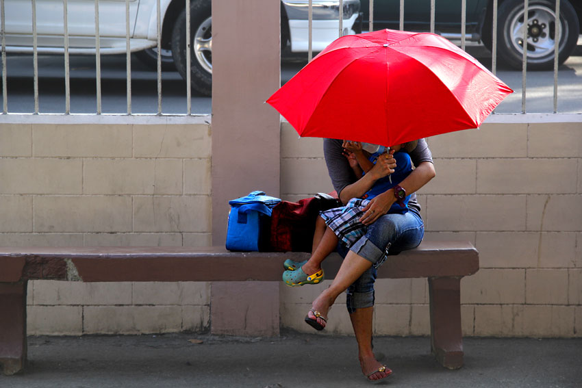 A mother and his son take a rest for a moment under her umbrella along San Pedro Cathedral. (Ace R. Morandante/davaotoday.com)