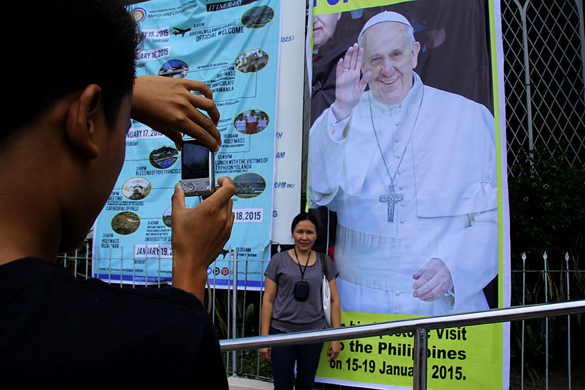 Emilyn Luna, 42, does not mind if Pope Francis will only visit Manila and Tacloban City in Leyte. Here, she poses for a moment snapshot taken by her nephew on a Pope's poster at the San Pedro Cathedral. (Ace R. Morandante/davaotoday.com)