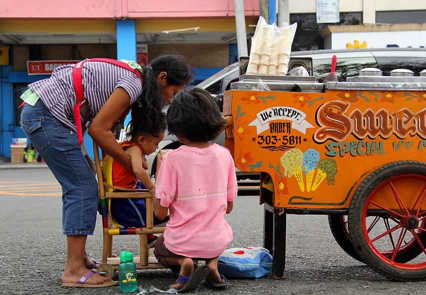 Bebeng, a 34 year old mother takes care of her one year old son Ivan, while her daughter Missy takes her lunch with her brother. She sells ice cream along San Pedro Street in Davao City while taking care of her siblings,  (Ace R. Morandante/davaotoday.com)