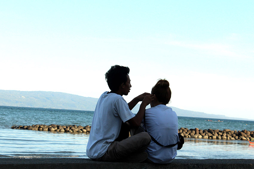 A teenage girl receives earrings from her boyfriend while dating beside the sea. (Medel V. Hernani/davaotoday.com)