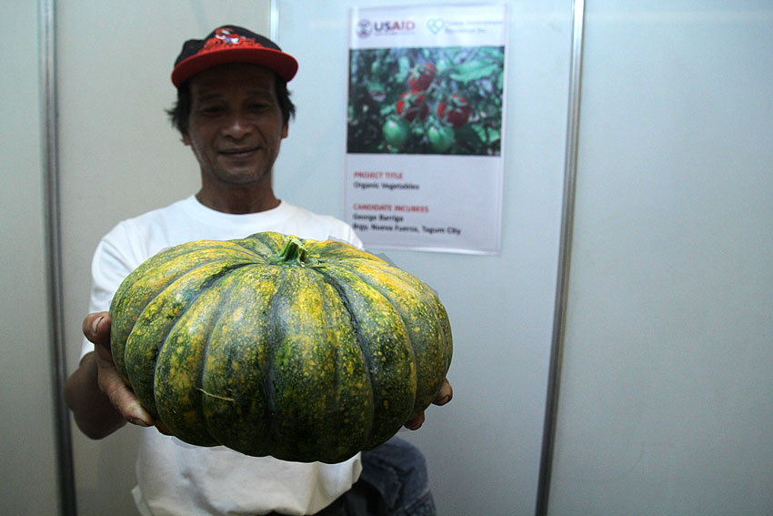 George Barriga, a farmer from Brgy. Nueva Fuerza, Tagum City, shows off a big squash which he said is organically grown. Barriga  is one of the 27 candidates to be funded by USAID introduced during the launching of Davao Business Incubators Project at a mall along JP Laurel Street. The event was initiated by the Tuazon Development Foundation Inc. (Ace R. Morandante/davaotoday.com)