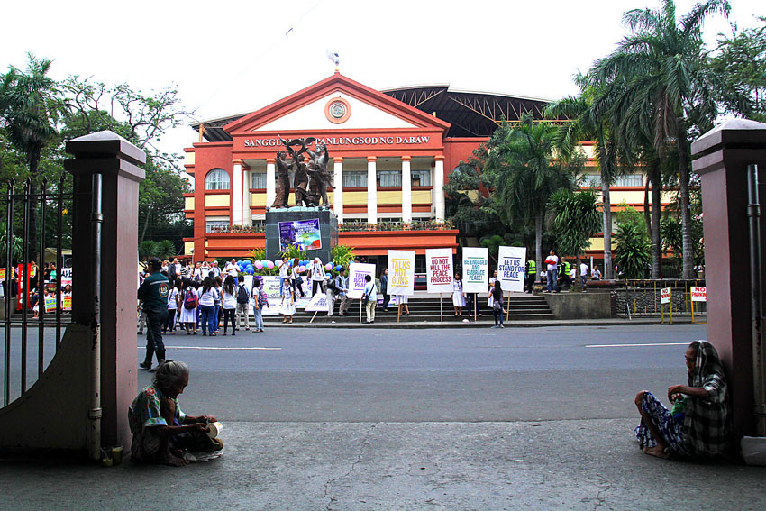 PEACE? Two old women of the Badjaos, a sea gypsy tribe, start their morning by begging in front of the San Pedro church in Davao City, while a group of peace advocates in front stages their protest action to call for peace in Mindanao amid the all-out offensives by the armed forces against Moro insurgents. (Ace R. Morandante/davaotoday.com)