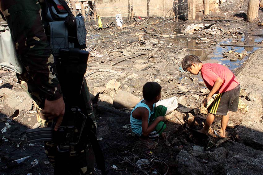 A soldier who provides security in the area, reminds the kids to be careful while scavenging for scrap materials.