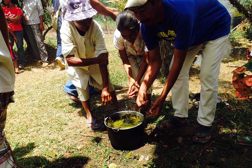 Old folks from Sitio Kabutoyen in North Upi, Maguindanao wash their hands in a pot filled with hot water and leaves of Pomelo and walked pass burning coconut husks after the necrological service they attended to drive away evil spirits. (Zea Io Ming C. Capistrano/davaotoday.com)