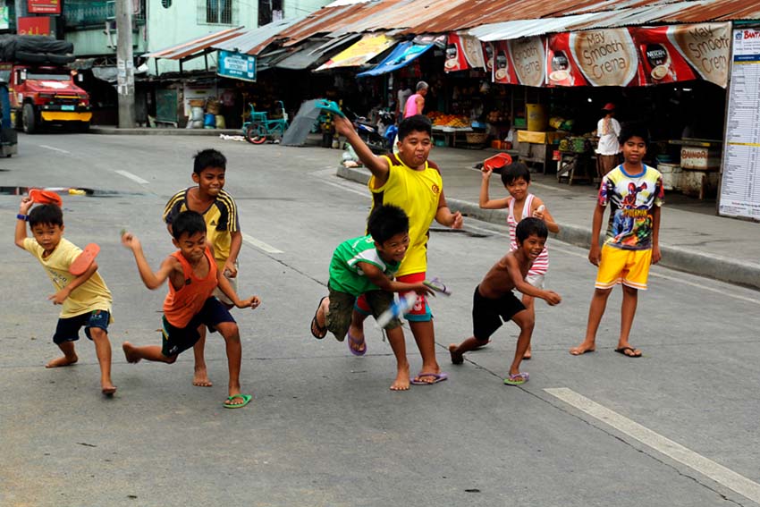 Children turn into a playground the closed road along Quezon Boulevard to enjoy the traditional game, Tumbang Preso. (Ace R. Morandante/davaotoday.com)