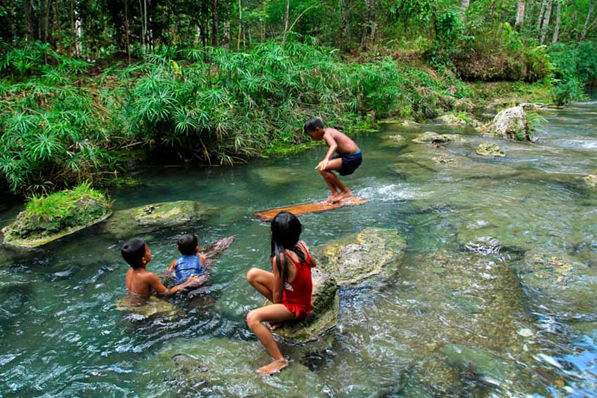 Using a piece wood as a surfboard, these kids are enjoying the river of the Hagimit Falls in the Island Garden City of Samal on a hot Sunday noon. (Ace R. Morandante/davaotoday.com)