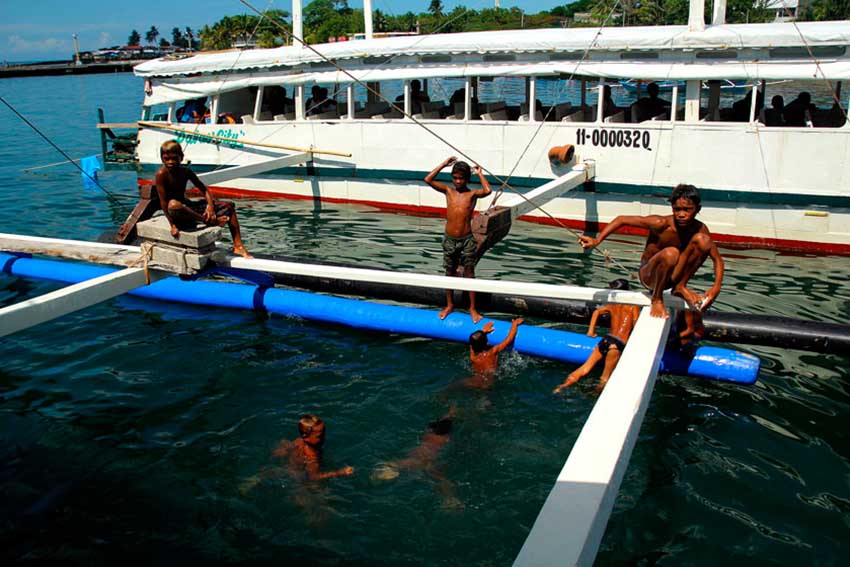 Sea gypsy kids (Badjao) patiently wait for passengers of a motor boat to throw them coins in the 12 to 15 feet-deep sea in Sta. Ana wharf. (Ace R. Morandante/davaotoday.com)