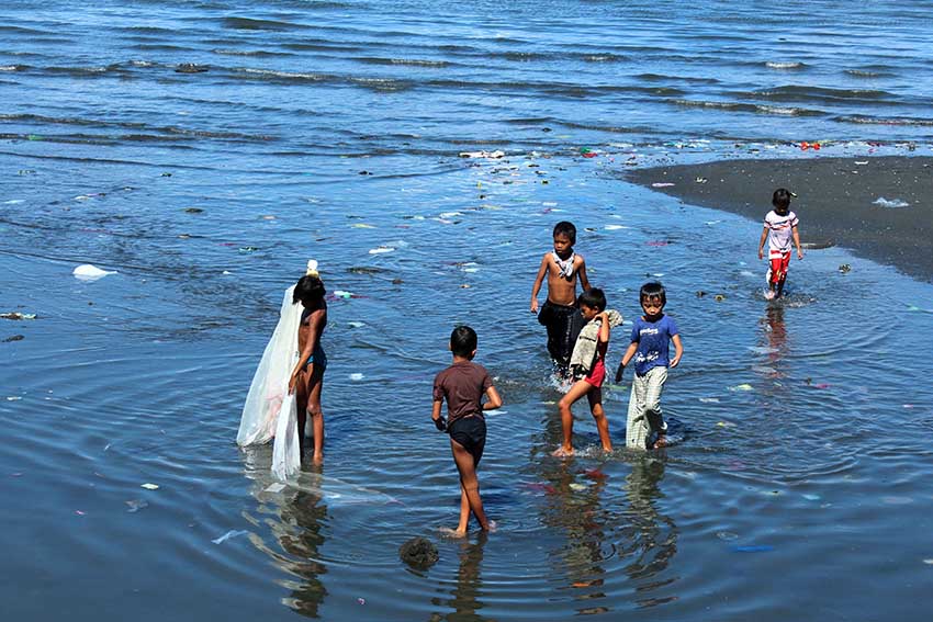 Teenagers spend their last days of summer roaming around the seashore using improvised net to catch small fish meters away from sea wall. (Medel V. Hernani/davaotoday.com)