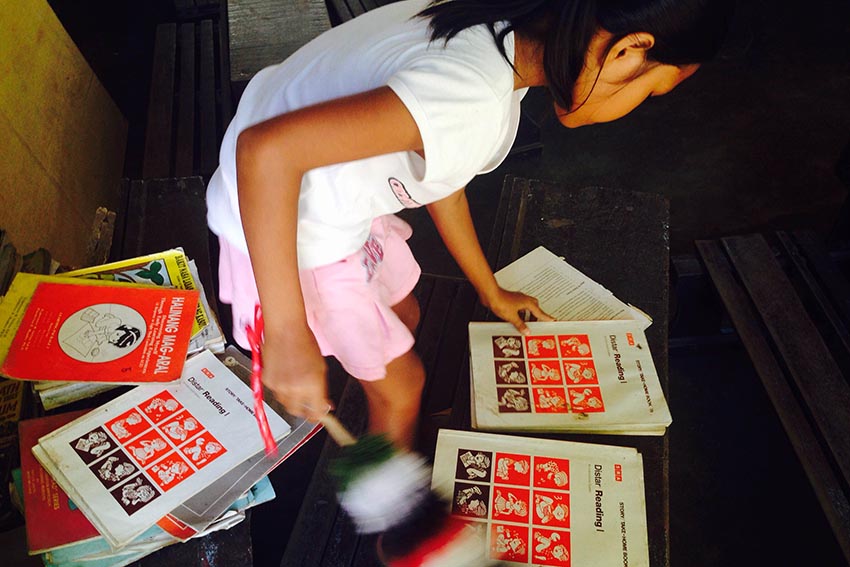 Jamaica, a Grade 5 student in Mintal Elementary School, helps out in cleaning books in a Grade 1 classroom during the third day of Brigada Eskwela. (Zea Io Ming C. Capistrano/davaotoday.com)