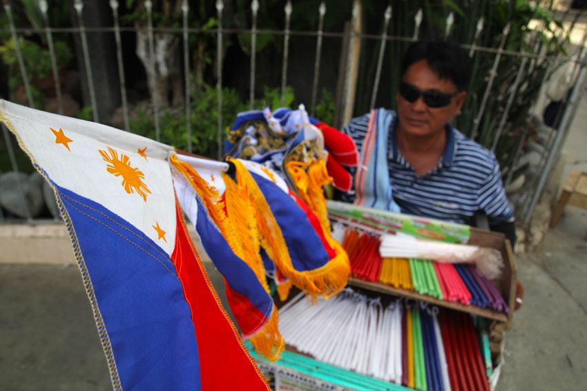 As the 117th anniversary of the declaration of Philippine Independence nears, Guillermo Udtohan, 54, grabs the opportunity to sell Philippine flaglets outside San Pedro Church in Davao City. He has been selling candles outside the church for two decades.  (Ace R. Morandante/davaotoday.com)