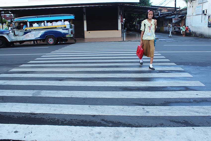 A student crosses the pedestrian lane going to San Pedro Street on her way to school early morning Friday. 