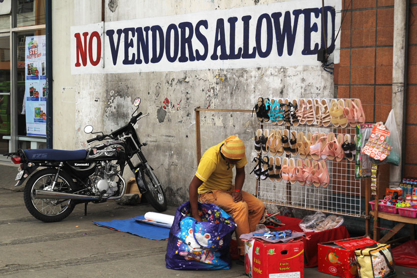 A man displays his product along San Pedro street amid the huge sign prohibiting vendors to sell their products within the vicinity. (Ace R. Morandante/davaotoday.com)