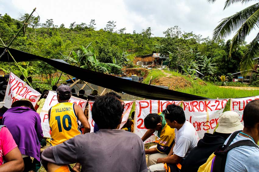 The farmers intently observe the operation site from the outside. They demand that operations be halted and all equipment be pulled out while negotiations are discussed.