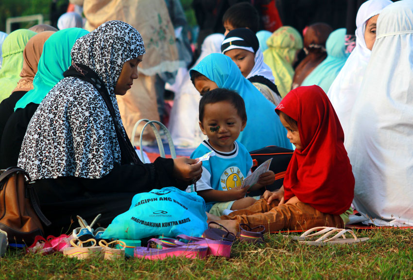 FAMILY. A mother and her children read Quran writings while waiting for the Sembahyang to start on Friday morning.