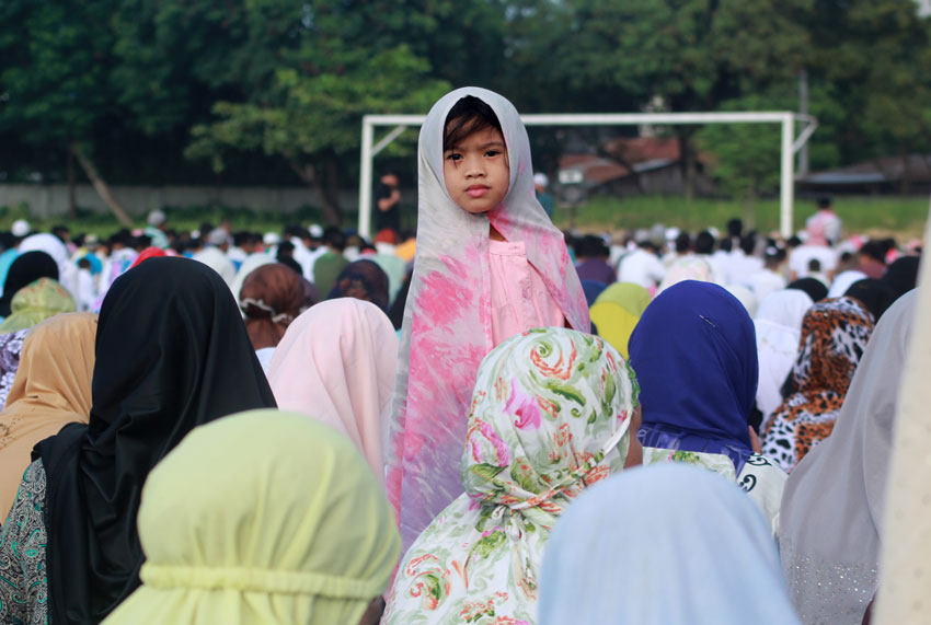 A Muslim child watches around the field, while elder Muslims listen to the preaching of their Imam during the celebration of the Eid'l Fitr on Friday at Tionko Football Field in Davao City.  (Ace R. Morandante/davaotoday.com)