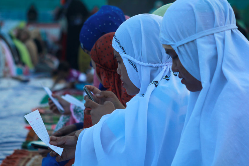 MUSLIM TEENS. A Muslim teener is busy texting while others read Quran's writing before the start of the Eid'l Fitr program at Tiongco Football Field in Davao City. 